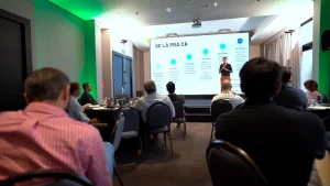 Um palestrante explicando estratégias de negócios com gráficos projetados em slides durante um evento corporativo