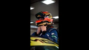 Piloto ajustando o capacete antes de entrar na pista em evento de corrida